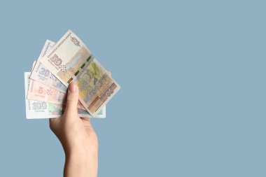 Mavi arka planda Bulgar lev banknotlarını tutan kadın