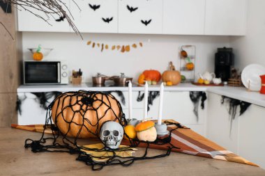 Kafatası ve mumlarla dolu Cadılar Bayramı balkabakları mutfaktaki masada