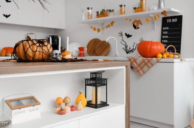 Cadılar Bayramı için beyaz tezgah ve masalarla dekore edilmiş aydınlık mutfağın içi.