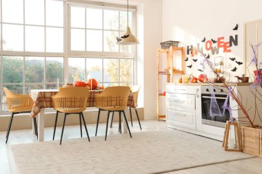 Cadılar Bayramı için beyaz tezgah ve yemek masasıyla dekore edilmiş hafif mutfağın içi.