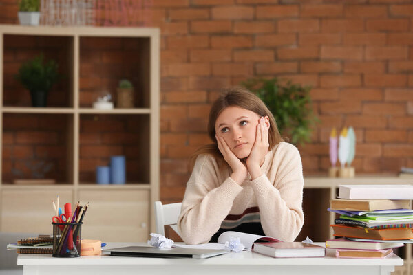 Уставшая девочка-подросток делает уроки дома