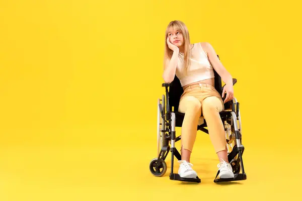 stock image Thoughtful young woman in wheelchair on yellow background