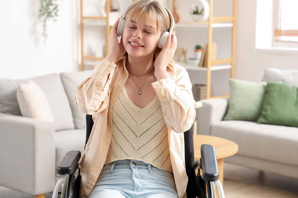 stock image Young woman with headphones in wheelchair at home