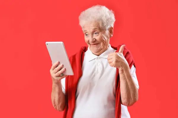 Senior Woman Tablet Computer Showing Thumb Red Background — Stock Photo, Image