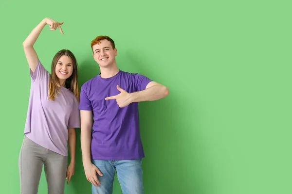 Casal Jovem Apontando Para Suas Camisetas Fundo Verde — Fotografia de Stock