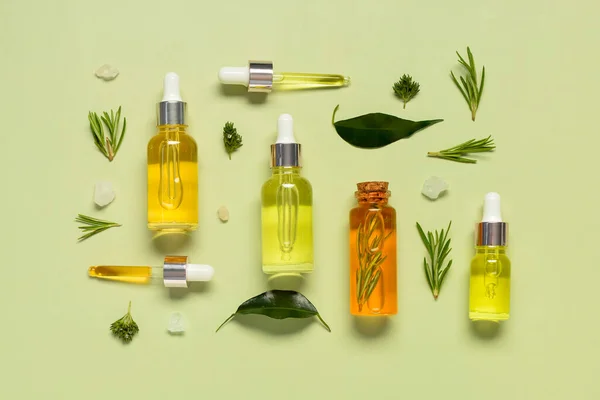 stock image Bottles of different healthy essential oils with herbs on pale green background