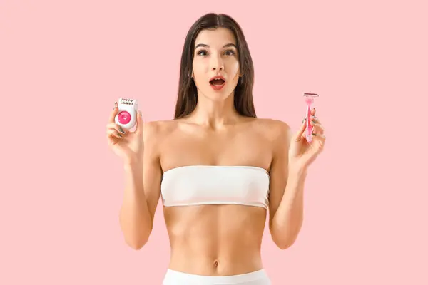 Shocked young woman with epilator and razor on pink background