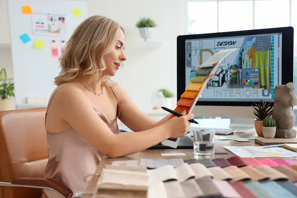 Ofisteki masada kumaş örnekleriyle çalışan kadın iç mimar.