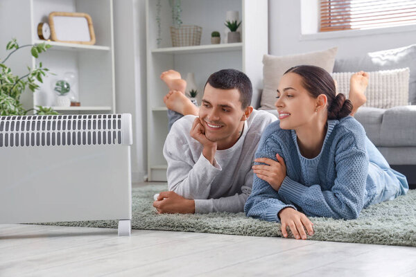 Young couple warming near radiator at home