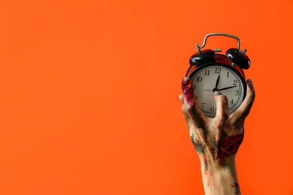 オレンジ色の背景に目覚まし時計が付いているゾンビ手 ハロウィーンのお祝い — ストック写真