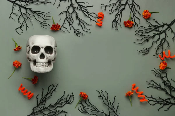 Frame made from Halloween skull, marigold flowers and branches on grey background