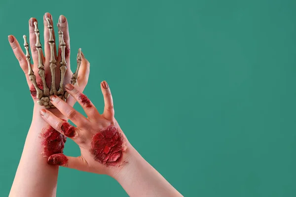 Zombie hands with skeleton hand on green background. Halloween celebration