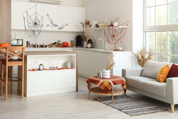 白いカウンターおよびソファーが付いているハロウィーンのために飾られる軽い台所の内部 — ストック写真