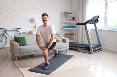 Sportif genç adam evde egzersiz yapıyor.