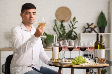 Genç şarap garsonu mutfakta bir bardak şarapla