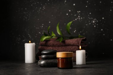 Kremalı kavanoz ve siyah arka planda spa taşları