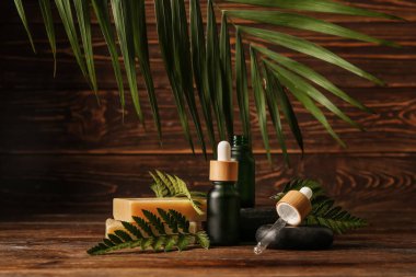 Ahşap arka planda gerekli yağ şişeleri, sabun barları ve spa taşları