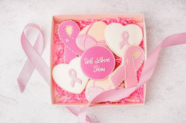 Pembe kurabiyeli kutu ve beyaz grunge arka planda kurdele. Göğüs kanseri farkındalığı konsepti