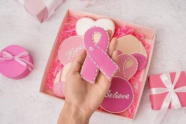 Beyaz grunge arka planda kurdele şeklinde pembe kurabiye tutan bir kadın. Göğüs kanseri farkındalığı konsepti