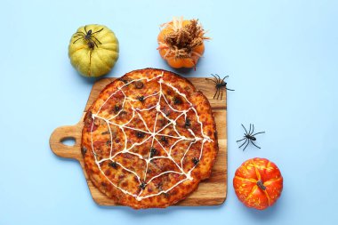 Mavi arka planda Cadılar Bayramı partisi için örümcekli ve balkabaklı ahşap pizza tahtası.
