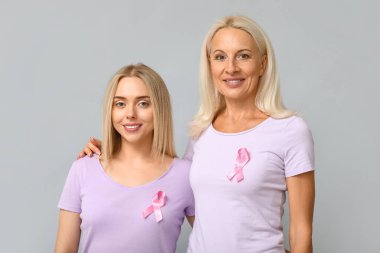 Gri arka planda pembe kurdeleli kadınlar. Göğüs kanseri farkındalığı konsepti
