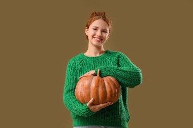 Yeşil arka planda balkabağı olan genç bir kadın.