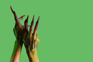 Yeşil arka planda pençeleri olan cadının elleri. Cadılar Bayramı