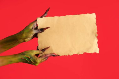 Kırmızı arka planda boş kağıtları olan bir cadı. Cadılar Bayramı