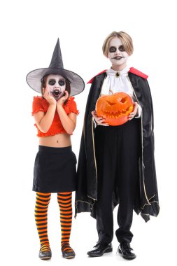 Cadılar Bayramı için giyinmiş küçük çocuklar ve beyaz arka planda balkabağı.