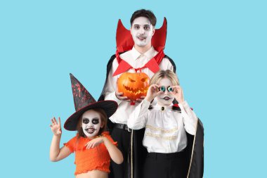 Mutlu aile Cadılar Bayramı için mavi arka planda giyinmiş.