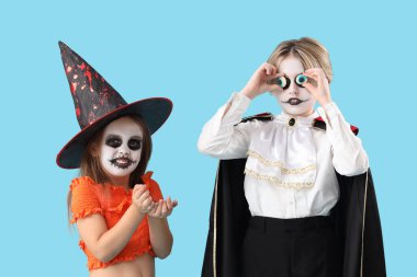 Cadılar Bayramı için giyinmiş küçük çocuklar mavi arka planda