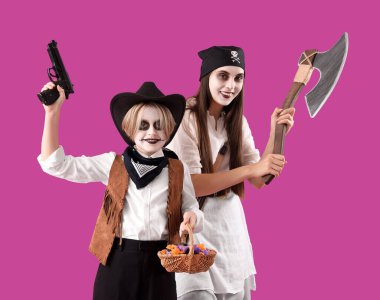 Küçük çocuk ve annesi Cadılar Bayramı için mor arka planda giyinmişler.