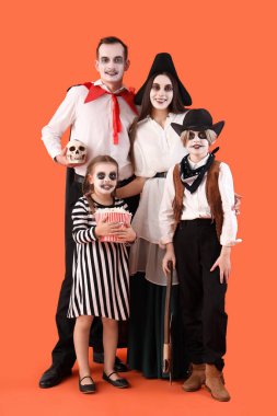 Cadılar Bayramı için giyinmiş mutlu aile turuncu arka planda patlamış mısır