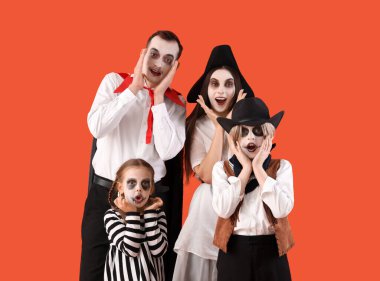Sürpriz aile Cadılar Bayramı için turuncu arka planda giyinmiş.
