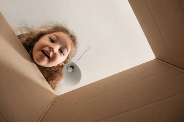 Cute little girl with open parcel at home, view from inside