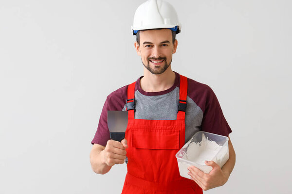 Мужчина-декоратор с шпаклеванным ножом и штукатуркой на светлом фоне