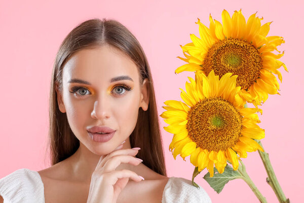 Молодая женщина с красивым ароматом подсолнухов на розовом фоне