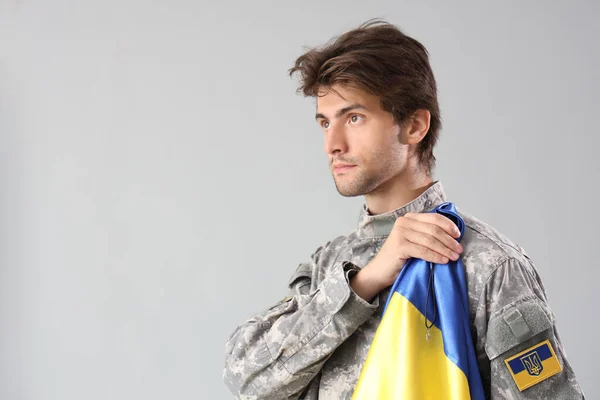 灰色の背景にウクライナの旗を持つ若い男性兵士 — ストック写真