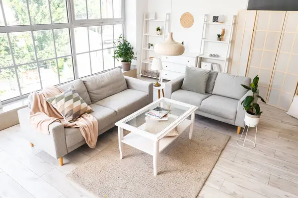 Gri kanepeleri ve kahve masası olan aydınlık oturma odasının içinde.