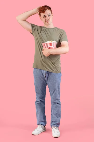Nachdenklicher Junger Rotschopf Mit Eimer Popcorn Auf Rosa Hintergrund — Stockfoto