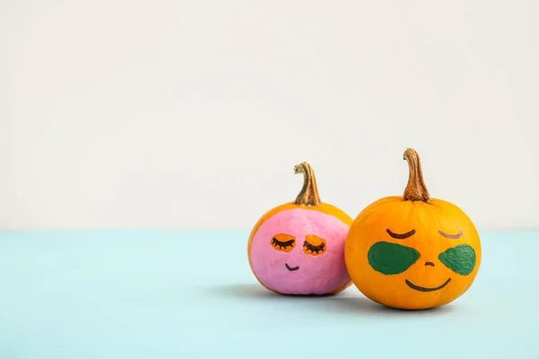 Pumpkins with mask and under-eye patches on blue table