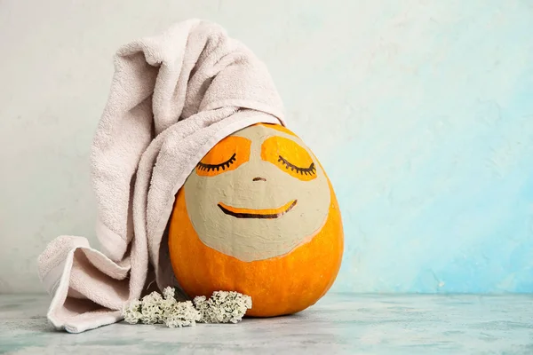 Pumpkin with clay mask, towel and flowers on grunge table