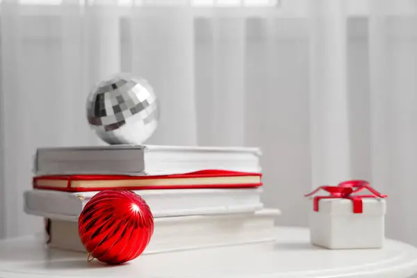 Christmas balls with books and gift on table in room, closeup