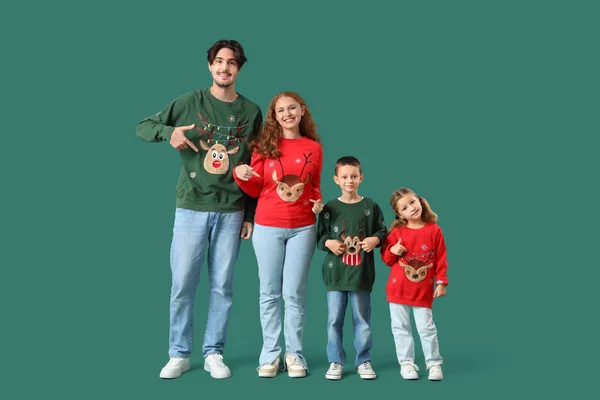 Happy family in warm sweaters on green background
