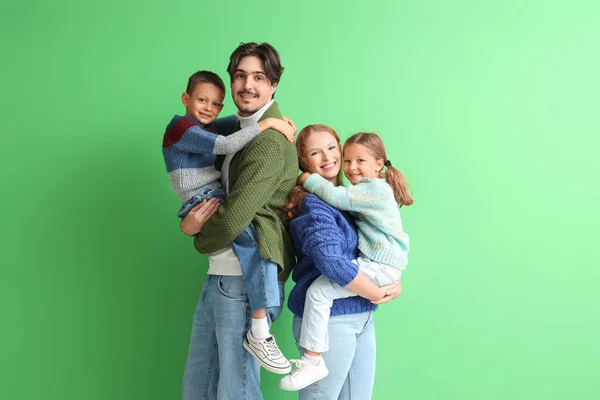 Happy family in warm sweaters on green background