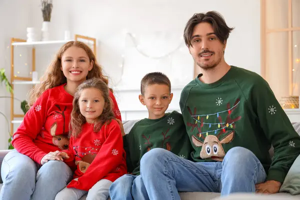 Happy family in warm sweaters sitting on sofa at home