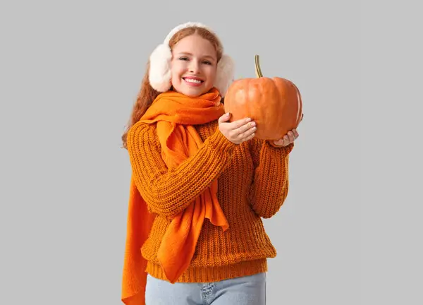 Young woman with pumpkin on light background