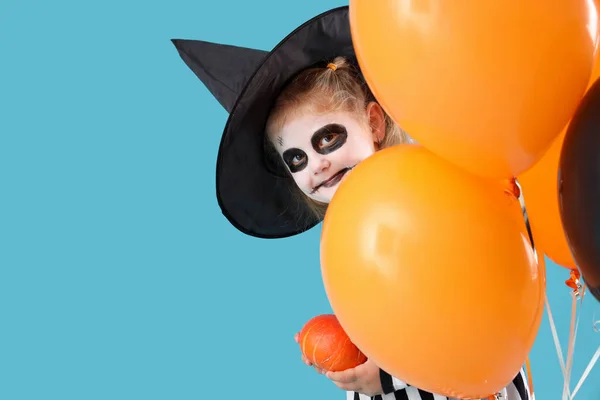 Little girl dressed for Halloween with balloons on blue background, closeup