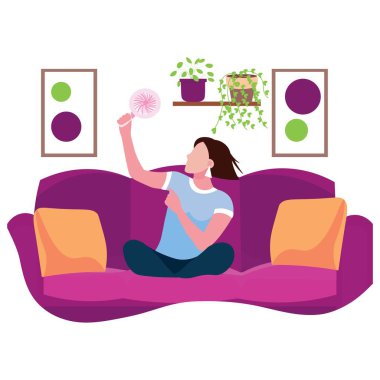 Elektrikli vantilatörlü kadın evdeki kanepede oturuyor.