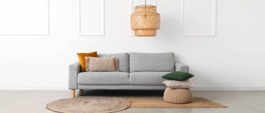 Gri kanepe, puf ve yastıklı aydınlık oturma odasının içi.